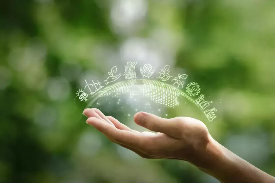 Offene Hand hält symbolische grüne Welt mit Icons zu erneuerbaren Energien, ESG und nachhaltiger Entwicklung.